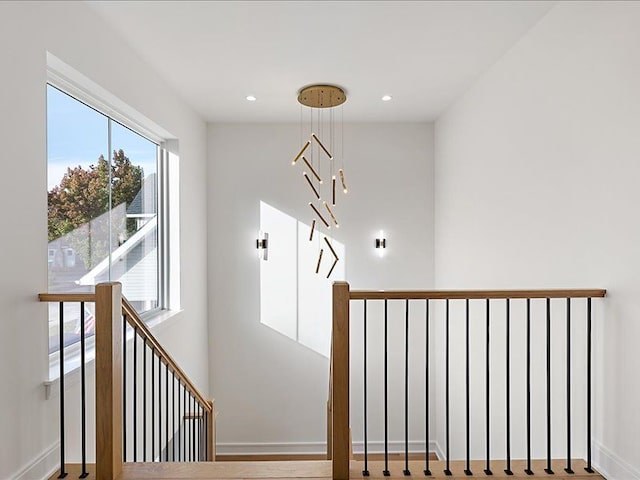 staircase featuring wood-type flooring and a notable chandelier