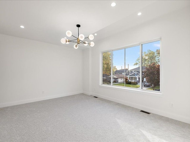 carpeted empty room with an inviting chandelier