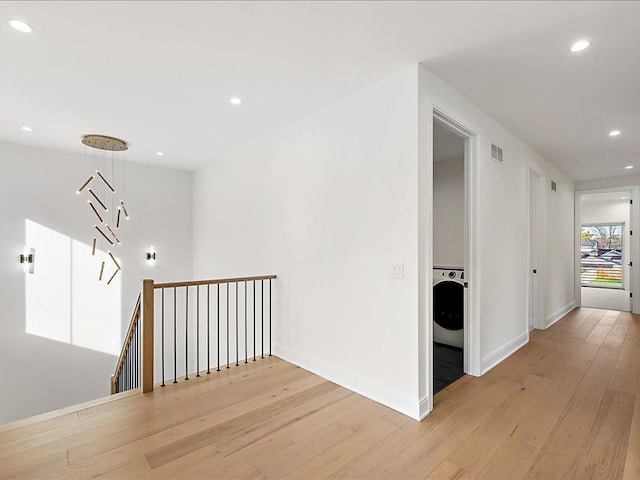 corridor with light hardwood / wood-style floors and washer / dryer