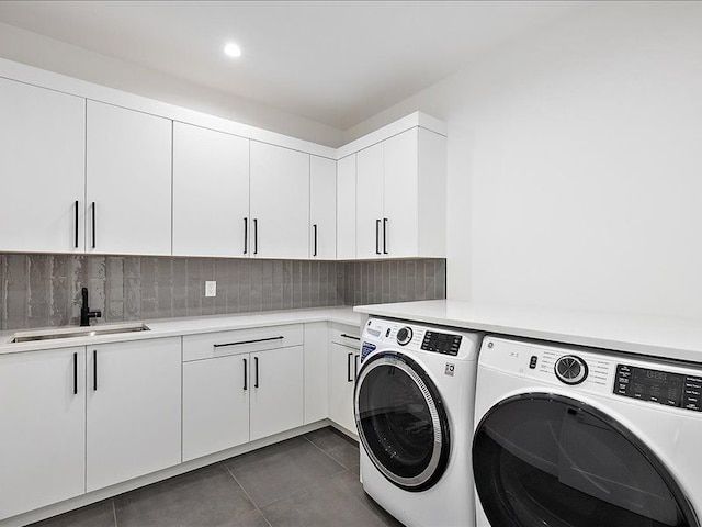 laundry area with washer and clothes dryer, sink, cabinets, and dark tile patterned flooring