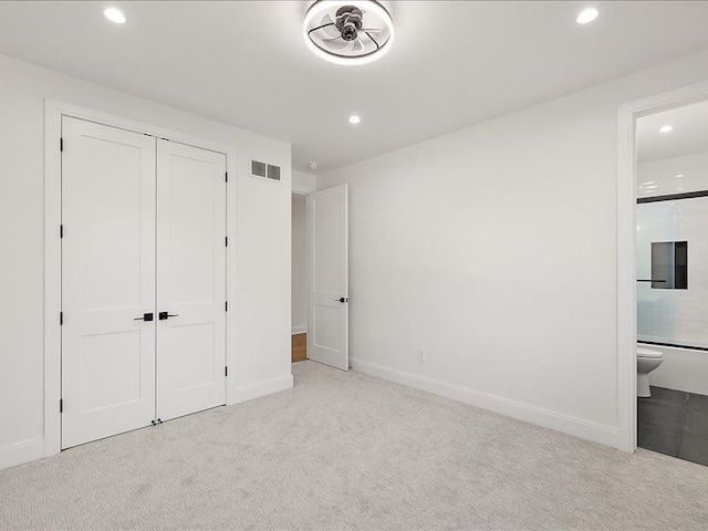 unfurnished bedroom with light carpet, connected bathroom, and a closet