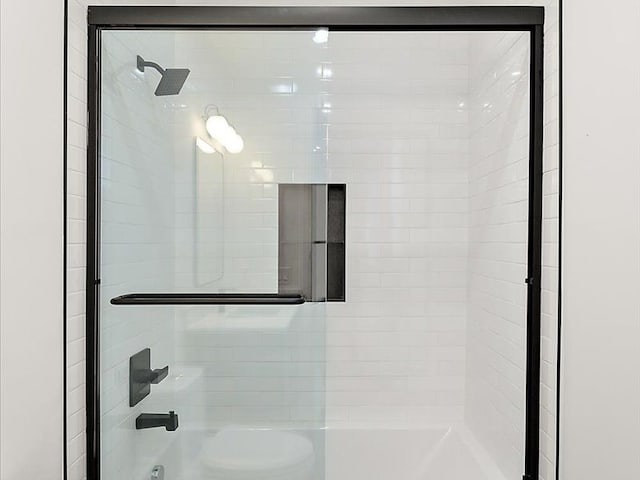 room details featuring shower / bath combination with glass door