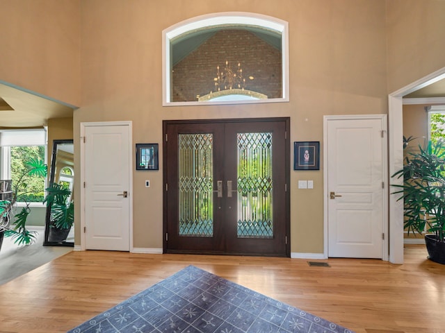 entryway with hardwood / wood-style flooring, a high ceiling, and french doors