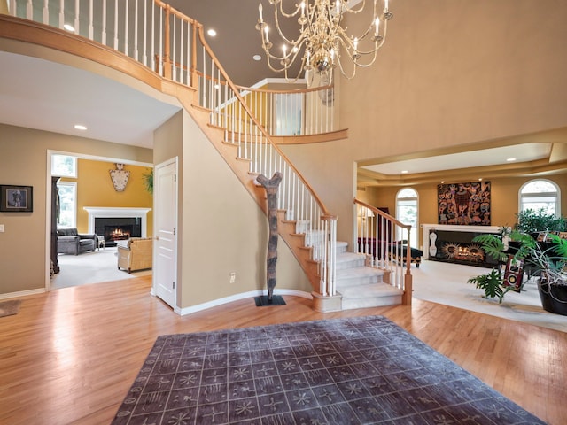 foyer entrance with a chandelier, hardwood / wood-style floors, a towering ceiling, and plenty of natural light