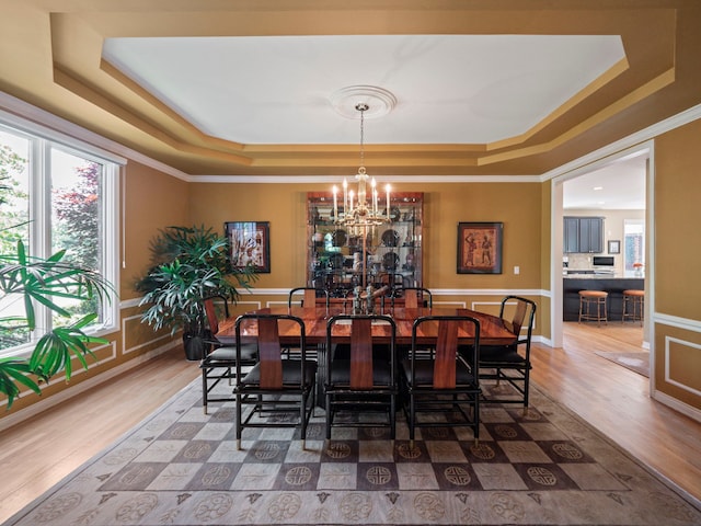 dining space with hardwood / wood-style flooring, a raised ceiling, and crown molding