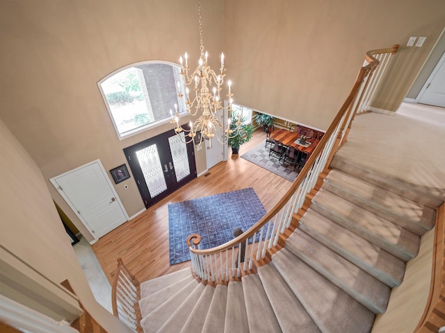 entrance foyer with french doors, hardwood / wood-style floors, a high ceiling, and an inviting chandelier