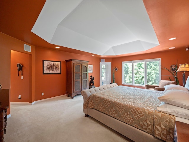 bedroom with light carpet and a tray ceiling