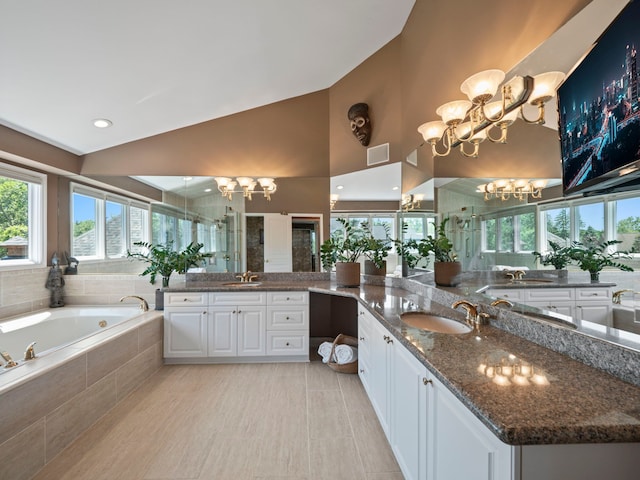 bathroom featuring tile patterned floors, vanity, vaulted ceiling, separate shower and tub, and a notable chandelier