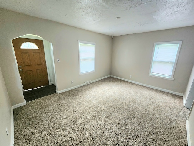 carpeted foyer entrance featuring a textured ceiling