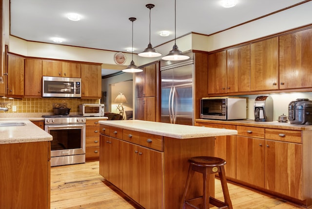 kitchen featuring sink, hanging light fixtures, light wood-type flooring, stainless steel appliances, and decorative backsplash