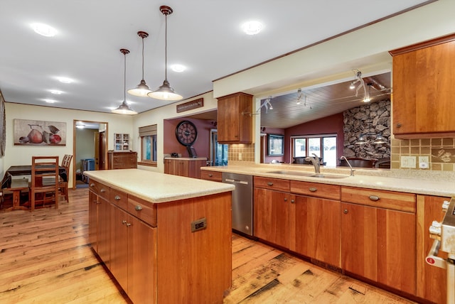 kitchen with tasteful backsplash, stainless steel dishwasher, sink, decorative light fixtures, and light hardwood / wood-style floors