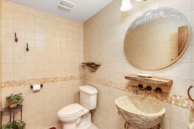 bathroom featuring tasteful backsplash, tile walls, and toilet