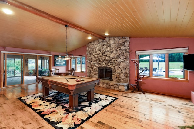 game room with pool table, a stone fireplace, lofted ceiling with beams, and light wood-type flooring