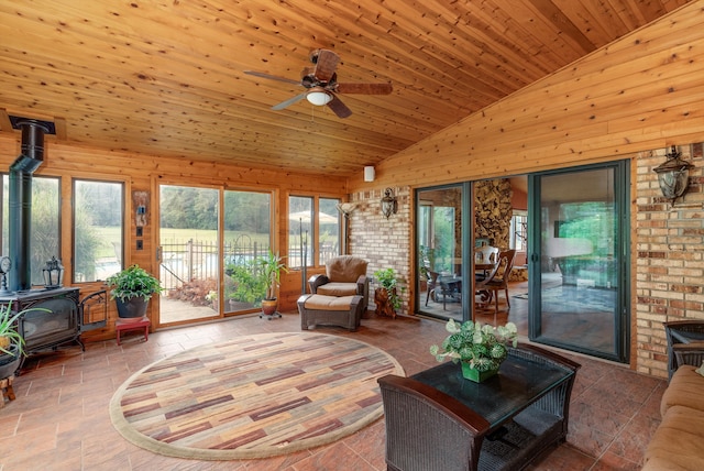 sunroom featuring wood ceiling, ceiling fan, vaulted ceiling, and a wood stove