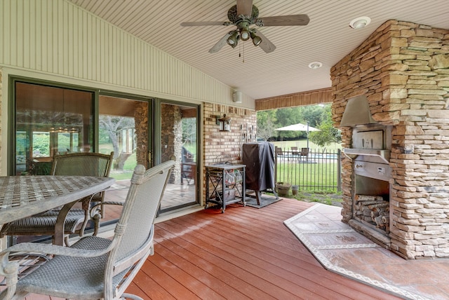 wooden deck featuring ceiling fan, area for grilling, and an outdoor stone fireplace