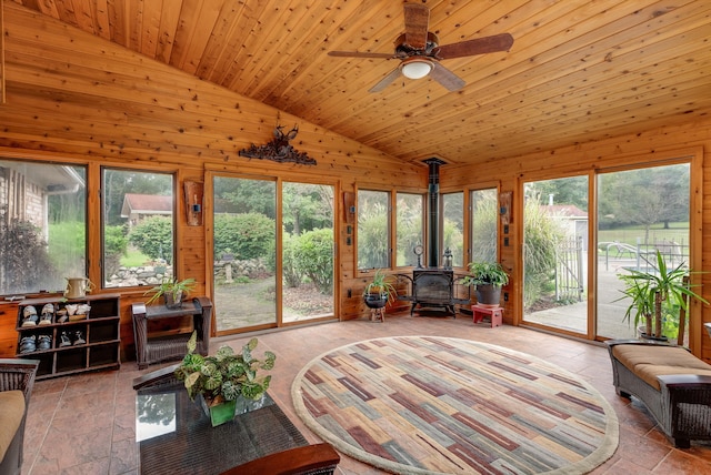 sunroom / solarium with wood ceiling, ceiling fan, lofted ceiling, and a wood stove