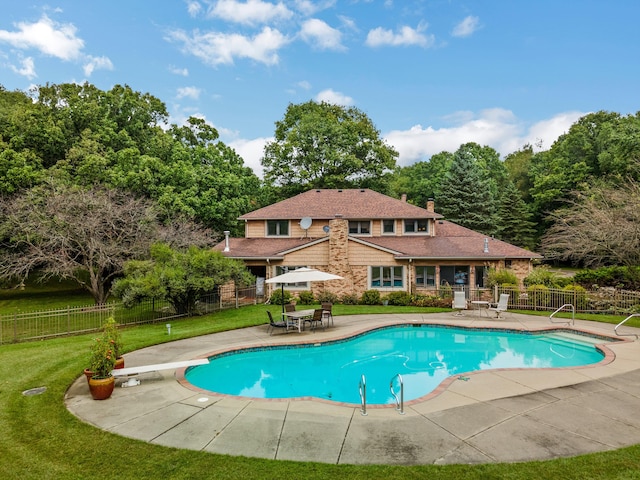 view of pool with a diving board, a patio area, and a lawn