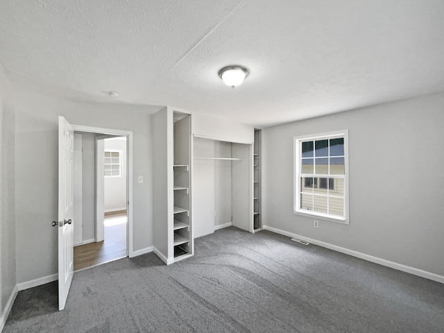 unfurnished bedroom with a closet, dark carpet, and a textured ceiling