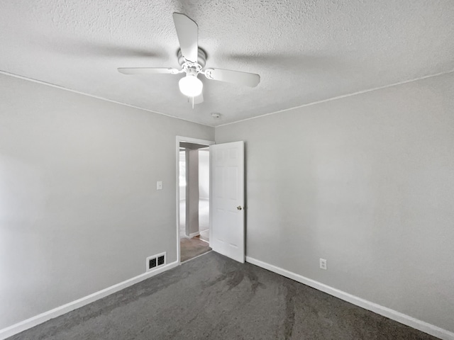 spare room with ceiling fan, a textured ceiling, and dark colored carpet