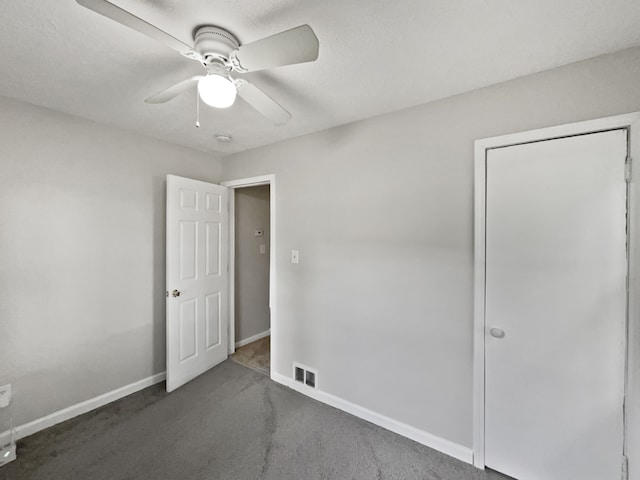 unfurnished bedroom with ceiling fan, dark carpet, and a textured ceiling