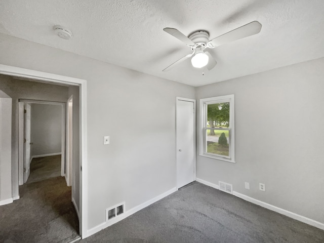 empty room with dark colored carpet, a textured ceiling, and ceiling fan