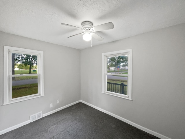 carpeted empty room featuring ceiling fan, a healthy amount of sunlight, and a textured ceiling