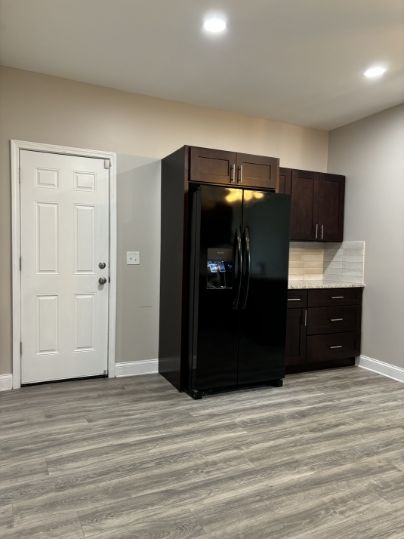 kitchen featuring black fridge with ice dispenser, dark brown cabinets, and light wood-type flooring