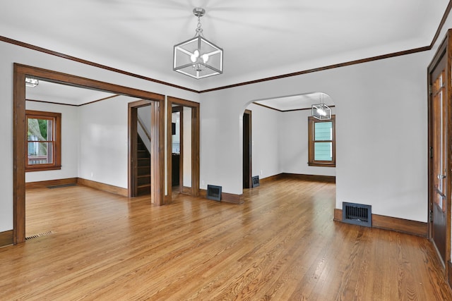 unfurnished room with an inviting chandelier, light hardwood / wood-style flooring, and crown molding