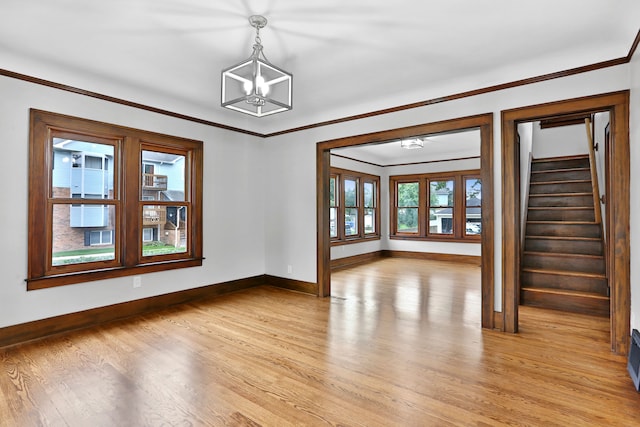 spare room with a notable chandelier, crown molding, and light hardwood / wood-style flooring