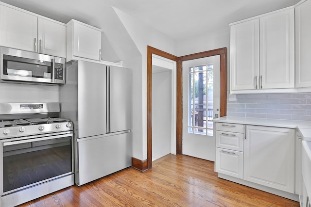 kitchen with decorative backsplash, light hardwood / wood-style floors, white cabinetry, and stainless steel appliances