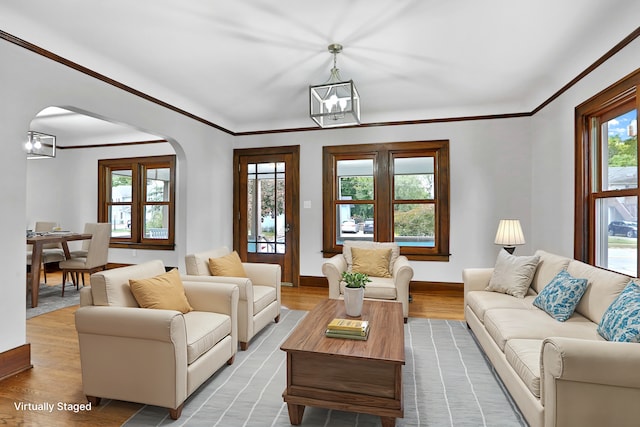 living room with light wood-type flooring, crown molding, and a notable chandelier