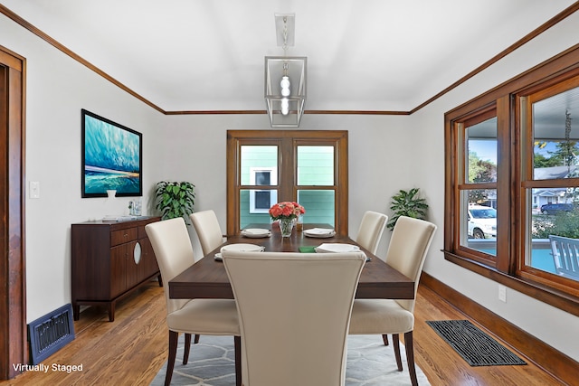 dining space featuring a healthy amount of sunlight, light hardwood / wood-style floors, and ornamental molding