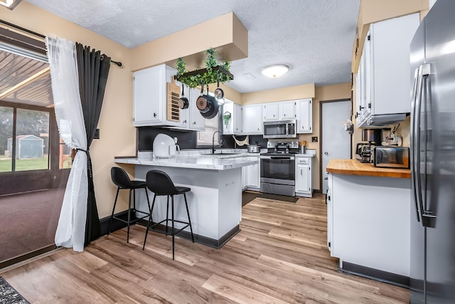 kitchen with stainless steel appliances, kitchen peninsula, sink, and white cabinets