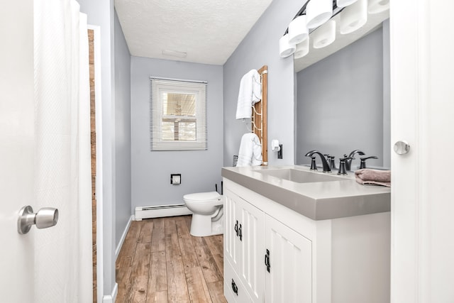 bathroom with toilet, a textured ceiling, baseboard heating, vanity, and hardwood / wood-style flooring