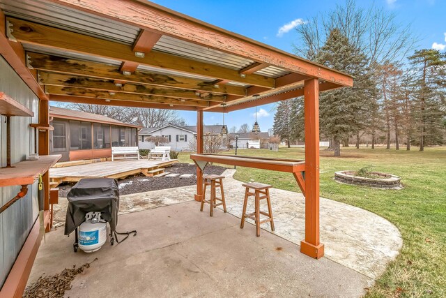 view of patio / terrace with a deck, a sunroom, and an outdoor fire pit