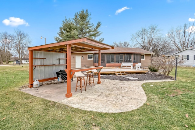 back of house featuring a sunroom, a lawn, a deck, and a patio area