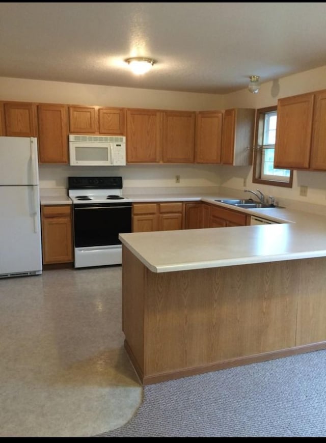 kitchen with kitchen peninsula, white appliances, and sink