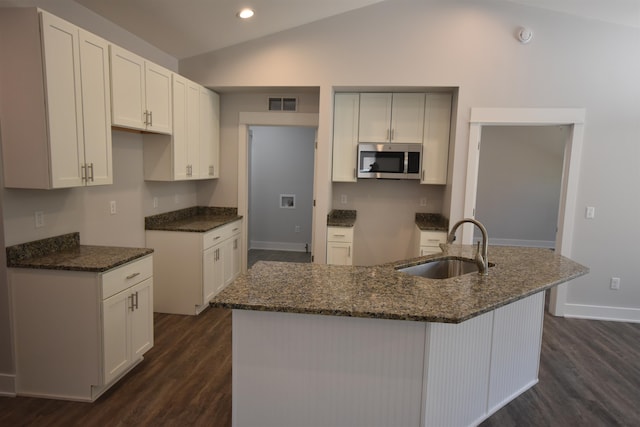 kitchen with a center island with sink, white cabinetry, lofted ceiling, and sink