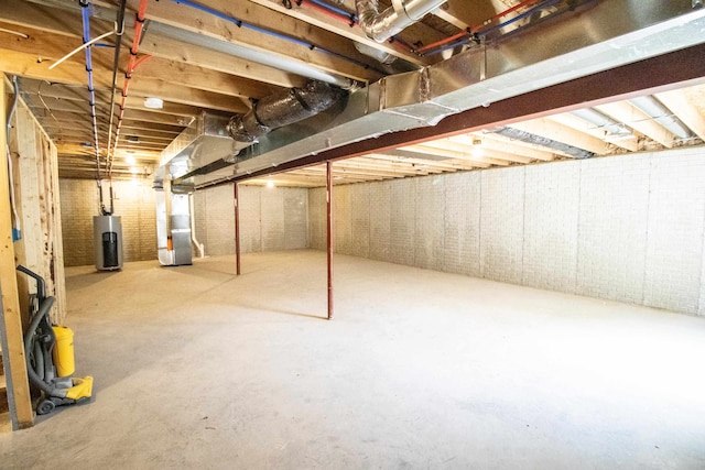 basement featuring heating unit, water heater, and brick wall