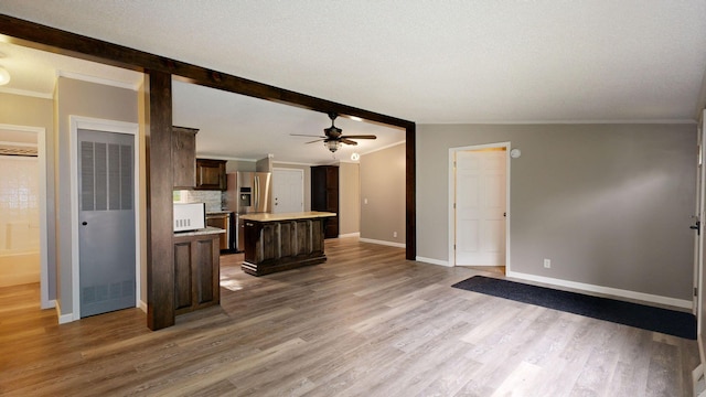 unfurnished living room with ceiling fan, vaulted ceiling with beams, wood-type flooring, a textured ceiling, and ornamental molding