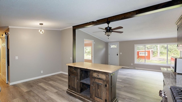 kitchen with ceiling fan, a center island, vaulted ceiling with beams, decorative light fixtures, and light wood-type flooring