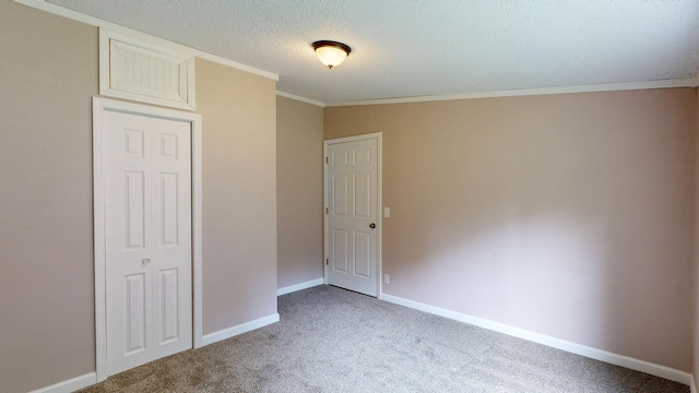 unfurnished bedroom featuring carpet flooring, ornamental molding, a textured ceiling, and a closet