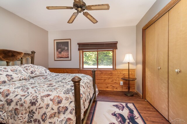 6610 E Arnold Lake Rd, Harrison, MI 48625 - bedroom with wood finished floors, wainscoting, a closet, ceiling fan, and wood walls