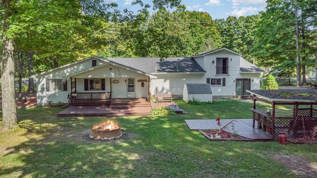 6610 E Arnold Lake Rd, Harrison, MI 48625 - rear view of property featuring a fire pit, a lawn, and a deck