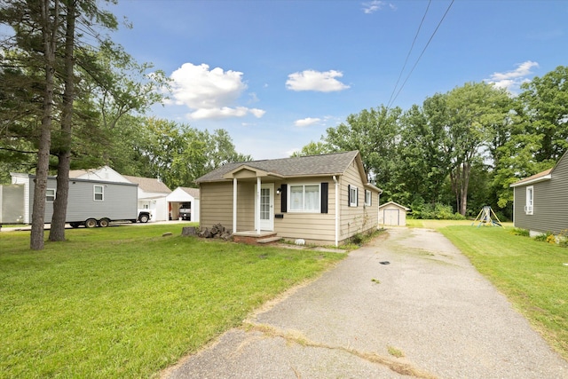 view of front of house with a garage, an outbuilding, and a front lawn