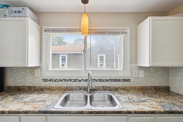 kitchen featuring tasteful backsplash, white cabinetry, sink, and decorative light fixtures