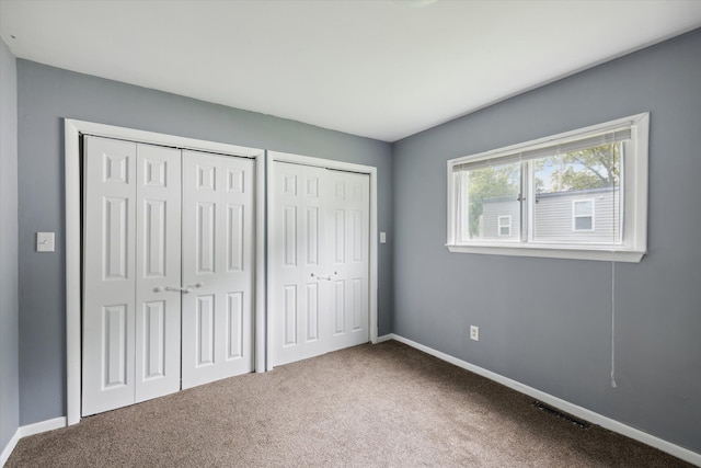 unfurnished bedroom featuring carpet floors and multiple closets