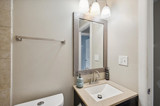 bathroom with a notable chandelier, vanity, and toilet