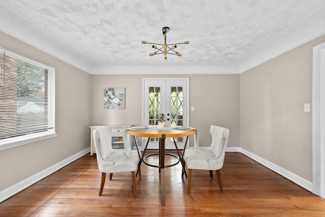 dining area with a textured ceiling, hardwood / wood-style floors, a healthy amount of sunlight, and french doors