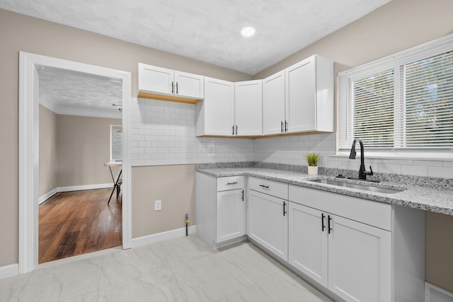18272 Ohio St, Detroit, MI 48221 - kitchen with a sink, light stone countertops, decorative backsplash, white cabinetry, and baseboards
